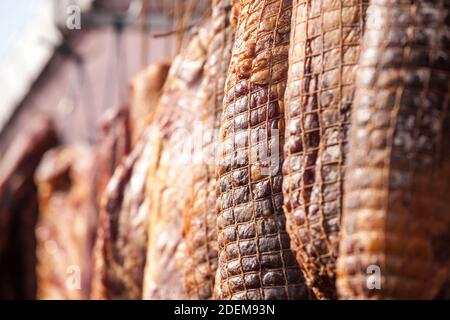 Serbischer Schinken, genannt prsut, italienischer Stil, ähnlich wie Prosciutto crudo, eingewickelt in ein Schinkennetz, das in der Landschaft Serbiens hängt. Prosciutto ist ein Typi Stockfoto