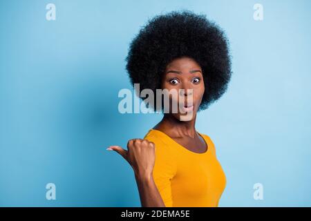 Foto-Portrait überrascht überrascht schwarz enthäutet Mädchen zeigt mit Finger auf leeren Raum isoliert auf lebendigen blauen Hintergrund Stockfoto