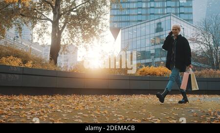 Junge blonde Frau in Winterkleidung sprechen am Telefon nach dem Einkaufen. Spätherbst oder Winter. Hochwertige Fotos Stockfoto