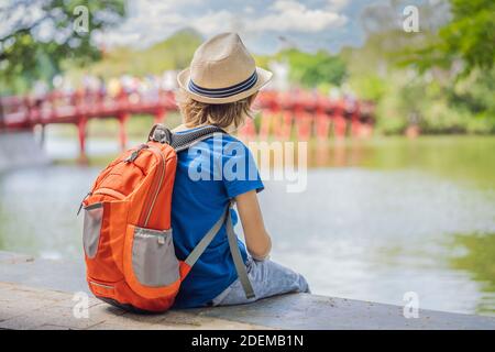 Kaukasischer Junge Tourist auf dem Hintergrund der Roten Brücke in der Öffentlichkeit park Garten mit Bäumen und Reflexion in der Mitte von Hoan Kiem See in der Innenstadt von Hanoi Stockfoto