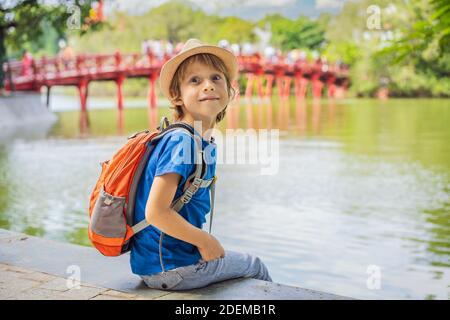 Kaukasischer Junge Tourist auf dem Hintergrund der Roten Brücke in der Öffentlichkeit park Garten mit Bäumen und Reflexion in der Mitte von Hoan Kiem See in der Innenstadt von Hanoi Stockfoto