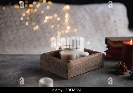 Kerzen in der Holzkiste isoliert auf grauweißem Hintergrund. Girlande-Lichter. Das Konzept der häuslichen Atmosphäre und Komfort, Urlaub, romantische Datum, Winter, Komfort zu Hause, drinnen, Weihnachten oder Neujahr. Stockfoto