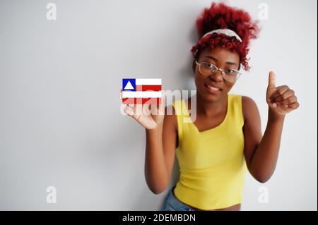 Brasilianische Frau mit afro Haar halten Bahia Flagge isoliert auf weißem Hintergrund, zeigen Daumen nach oben. Staaten von Brasilien Konzept. Stockfoto