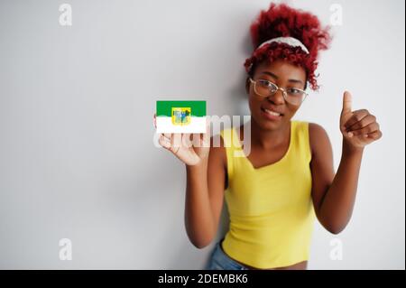 Brasilianische Frau mit afro Haar halten Rio Grande do Norte Flagge isoliert auf weißem Hintergrund, zeigen Daumen nach oben. Staaten von Brasilien Konzept. Stockfoto