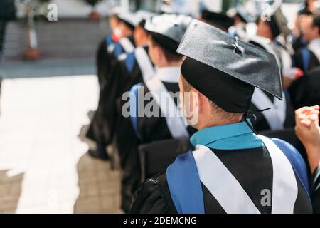 Erfolgreiche Absolventen in akademischen Kleidern, bei Abschluss, sitzen in Form von Absolventen, kann für Werbung verwendet werden, Stockfoto