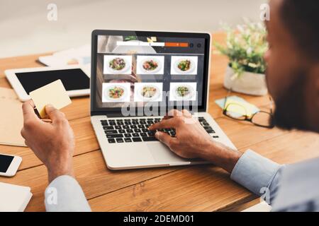 African Geschäftsmann Bestellung Mittagessen Online Auf Laptop Sitzen Im Büro Stockfoto