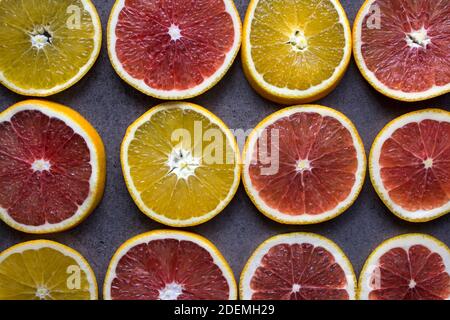 Rot orange Fruchtkreise auf dunkelgrauem Hintergrund. Nahaufnahme mit Zitrusstruktur. Juicy Orangen Draufsicht Foto. Stockfoto