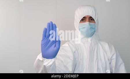 Haltestelle Covid-19. Ein Krankenschwester im Schutzanzug macht das Stoppschild mit seiner Hand in einem Krankenhaus. Tragen Sie eine Maske und Handschuhe. Stockfoto