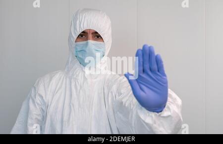 Haltestelle Covid-19. Ein Krankenschwester im Schutzanzug macht das Stoppschild mit seiner Hand in einem Krankenhaus. Tragen Sie eine Maske und Handschuhe. Stockfoto