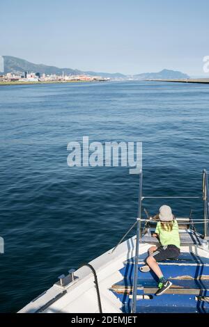 Junge auf dem Dock eines Bootes, der zum Meer hinausschaut Stockfoto