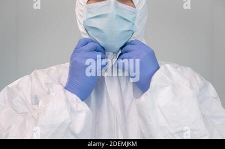 Eine Krankenschwester bereitet sich vor, indem sie während einer Coronavirus-Pandemie Schutzanzüge anlegt. Die Krankenschwester trägt einen PSA-Anzug, Handschuhe und eine OP-Maske im Krankenhaus Stockfoto