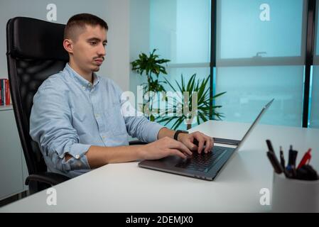 Seriöse junge Geschäftsmann sitzen und arbeiten mit einem modernen Laptop im Büro Schreibtisch. Männliche Unternehmer schreiben auf dem Computer am Arbeitsplatz. Kaukasische M Stockfoto
