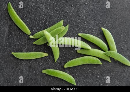 Erbsen auf nassem Schieferstein Hintergrund Stockfoto