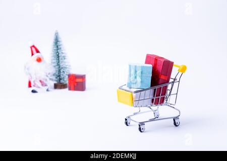 Miniaturwagen mit Geschenken auf weißem Hintergrund. Weihnachts- und Neujahrseinkaufskonzept. Nahaufnahme. Stockfoto