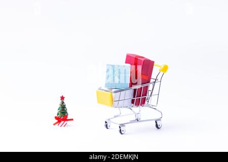 Miniaturwagen mit Geschenken auf weißem Hintergrund. Weihnachts- und Neujahrseinkaufskonzept. Nahaufnahme. Stockfoto