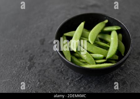 Erbsen in Schüssel auf nassem Schieferstein Hintergrund Stockfoto