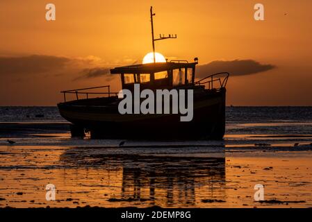 Sonne geht hinter einem festgemachtes, beachtes Boot in der Morgendämmerung auf, Sonnenaufgang am ersten Tag des meteorologischen Winters, Dezember 2020 in Southend on Sea, Essex, UK Stockfoto