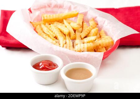 Knusprige Crinkle Pommes Frites mit Soße und Ketchup schneiden Stockfoto