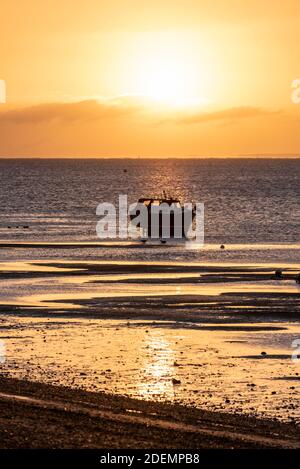 Sonne geht hinter einem festgemachtes, beachtes Boot in der Morgendämmerung auf, Sonnenaufgang am ersten Tag des meteorologischen Winters, Dezember 2020 in Southend on Sea, Essex, UK Stockfoto