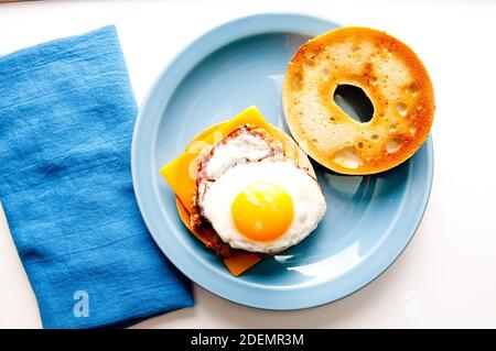 Gebratenes sunnyside-up-Ei auf einem Wurstpastete mit einem Bagel und Käse Stockfoto