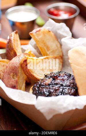 Ethisch angehobener Schweinefleischburger mit handgeschnittenen roten Kartoffelkeilen Und Gemüsestöcke nehmen Stock Foto Stockfoto