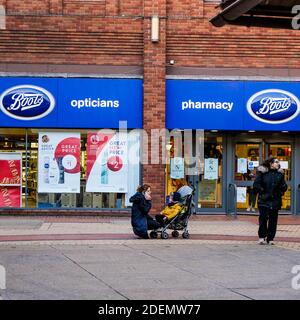 London UK, Dezember 01 2020, Mutter und Baby in EINEM Kinderwagen außerhalb der Boots Pharmacy Stockfoto