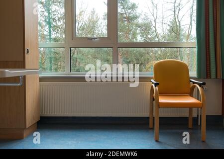 Ein Innenraum eines Krankenhauszimmers mit Stuhlfenster und Vorhängen, Konzept für Einsamkeit Stockfoto