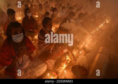 Peking, China. Dezember 2020. Hinduistische Anhänger sitzen zum Gebet mit brennendem Weihrauch und hellen Öllampen während des Rakher Upobash, einem religiösen Fastenfest, am 7. November 2020 in einem Tempel im Narayanganj Bezirk am Rande der bangladeschischen Hauptstadt Dhaka. Quelle: Xinhua/Alamy Live News Stockfoto