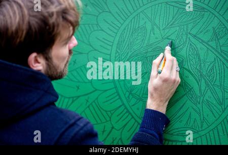Oldenburg, Deutschland. Dezember 2020. Sebastian von Zeberg von der Künstlergruppe 'die Jungs' für Wandgestaltung arbeitet an einem Kunstwerk vor dem Hauptbahnhof. Mit Street Art auf 24 Holzwänden entwerfen Oldenburger Künstler in diesem Jahr einen Adventskalender für die Öffentlichkeit. Jeden Tag wird ein Parkplatz in der Innenstadt bemalt. Quelle: Hauke-Christian Dittrich/dpa/Alamy Live News Stockfoto