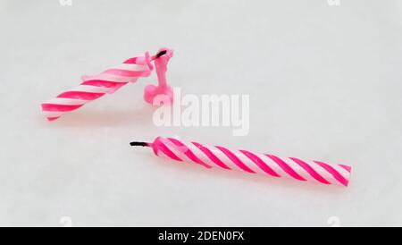 Zwei erloschene rosa Geburtstagskerzen mit schwarzen Dochten, die auf dem Tisch liegen. Stockfoto