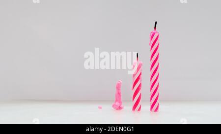 Drei ausgelöscht rosa Geburtstagskerzen in verschiedenen Höhen, auf einer Oberfläche Seite an Seite von kurz bis hoch platziert. Stockfoto