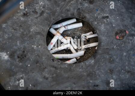 Zigarettenkippen im schwarzen Aschenbecher. Stockfoto