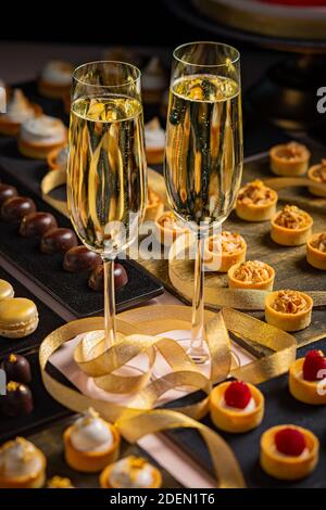 Zwei Gläser Champagner und eine Auswahl an süßen und herzhaften Snacks werden während einer Veranstaltung serviert. Stockfoto