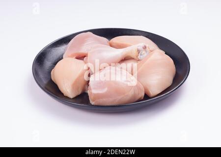 Rohes Huhn zartes Curry ohne Haut auf schwarz angeordnet geschnitten Platte mit weißem strukturiertem Hintergrund Stockfoto