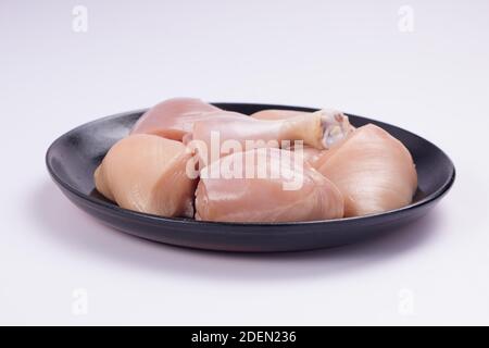 Rohes Huhn zartes Curry ohne Haut auf schwarz angeordnet geschnitten Platte mit weißem strukturiertem Hintergrund Stockfoto