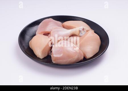 Rohes Huhn zartes Curry ohne Haut auf schwarz angeordnet geschnitten Platte mit weißem strukturiertem Hintergrund Stockfoto