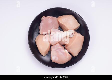 Rohes Huhn zartes Curry ohne Haut auf schwarz angeordnet geschnitten Platte mit weißem strukturiertem Hintergrund Stockfoto