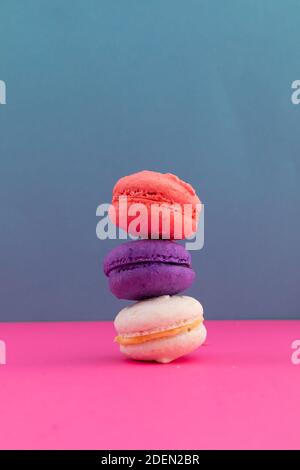 Nahaufnahme von weißen, lila und rosa Macarons auf rosa und blauen Hintergrund gestapelt Stockfoto
