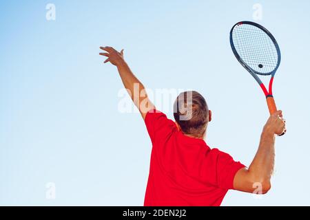 Junger professioneller Tennisspieler, der einen Service leistet Stockfoto