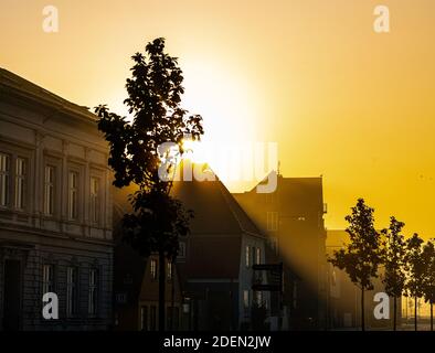 Die ersten Sonnenstrahlen brechen durch den Morgennebel über den Dächern der Stadt. . Hochwertige Fotos Stockfoto
