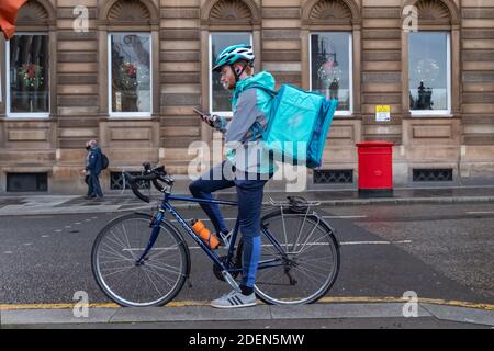 Glasgow, Schottland, Großbritannien. Dezember 2020. UK Wetter: Ein deliveroo Kurier Radfahrer mit seinem Handy in George Square. Kredit: Skully/Alamy Live Nachrichten Stockfoto