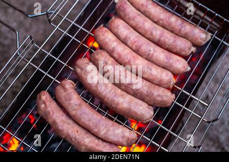 Die Grillwürste liegen auf dem Drahtgitter über dem Grill. Köstliche Fleischdelikatesse. Oktoberfest. Stockfoto