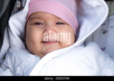 Säugling, Kindheit, Emotion Konzept - Nahaufnahme von niedlichen lächelnd Porträt Gesicht von braunen Augen mollig Neugeborenen wach zahnlos Baby 6-9 Monate alt Blick auf Stockfoto