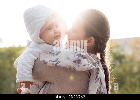 Säuglinge, Kindheit, Mutterschaft, Familie, Lifestyle-Konzept - glücklich junge Mutter in Brille halten Fett mollig Neugeborenen lächelnd Baby Mädchen 6 Monate alt in weiß Stockfoto