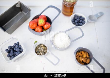 Beeren, Mehl und Nüsse in Behältern über dem weißen Zähler Stockfoto