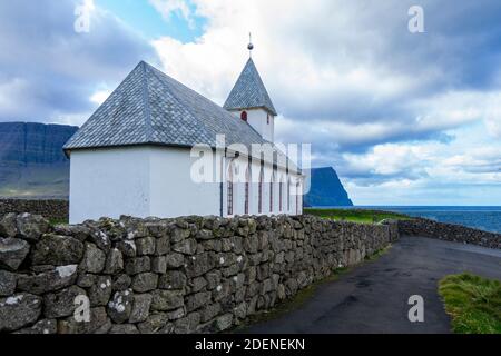 Blick auf die alte Kirche in Vidareidi auf der Insel Vidoy, Färöer, auf dem Hintergrund von herrlichen Bergen und Meer. Stockfoto