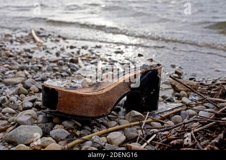 Gebrochener Schuh, von dem nur noch die Holzsohle übrig ist, liegt am Strand Stockfoto