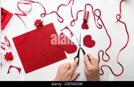 Valentinstag Scrapbook, Hochzeit oder andere Feiertag Dekorationen Hintergrund. Handgemachte Geschenk Grußkarte erstellen, schneiden. Die Hände der Frauen halten die Stockfoto