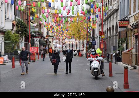 Menschen mit Schutzmasken spazieren entlang der Gerrard Street in Chinatown, London. Stockfoto