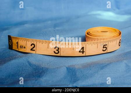 Ein altes flexibles Gummiband mit Metallspitze wird teilweise gewickelt und auf ein Stück blauem Stoff gelegt. Stockfoto